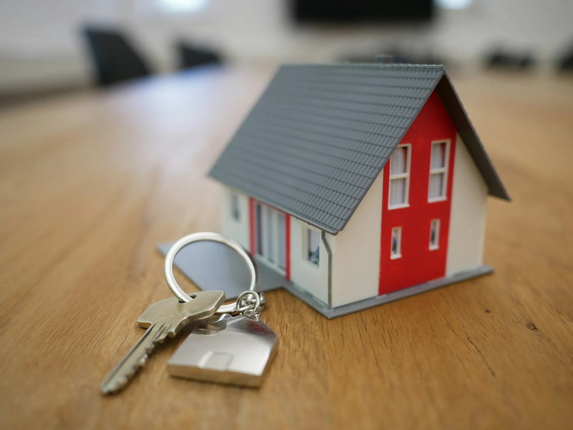 Keys on a ring next to a small model house on a wooden table