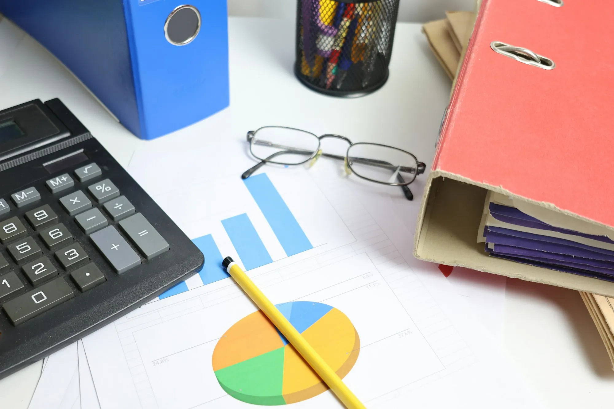 Calculator beside a pie chart, glasses and a binder, used to plan the buyer contingency period on a Shafter, California home purchase
