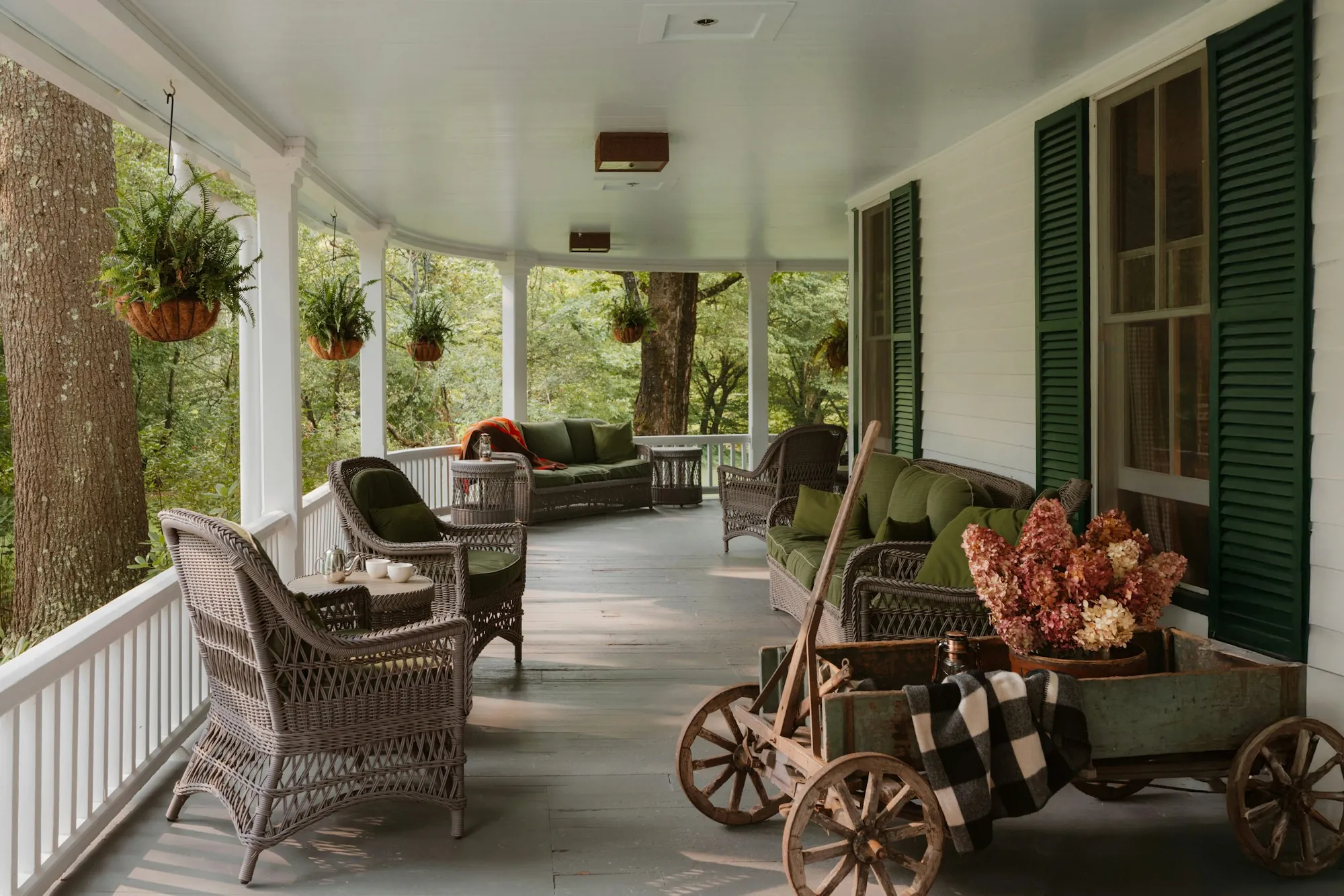 Wide covered front porch with wicker chairs and hanging plants
